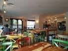Zona de comedor con mesas de madera y sillas de colores vibrantes
