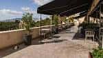 Terraza exterior con mesas dispuestas bajo toldos y vistas panorámicas del entorno