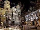 Vista nocturna de la Plaza del Justicia con la fuente iluminada y la iglesia al fondo