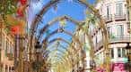 Calle Larios engalanada con estructuras de arcos decorativos para festividades locales
