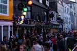 Ambiente festivo en el exterior del pub con iluminación decorativa y público