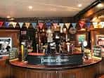 Barra principal del pub decorada con banderines y grifos de cerveza