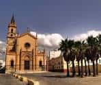 Perspectiva exterior de la parroquia desde la plaza con palmeras