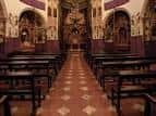 Vista del interior de la iglesia mostrando el pasillo central, los bancos y el altar