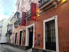 Fachada exterior del edificio de estilo sevillano con banderas rojas en los balcones