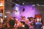 Interior del local durante un evento con público y el nombre del club proyectado en la pared
