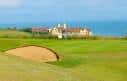 Vista del campo de golf con un búnker de arena en primer plano y el mar al fondo