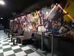 Interior del club con zona de sofás y pared decorada con pósteres de artistas