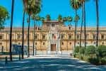 Vista frontal de la fachada principal del Parlamento de Andalucía con palmeras