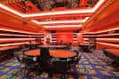 Interior de la sala de juegos con mesas de póker y ambientación en tonos rojos