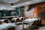 Salón principal del restaurante con mesas preparadas y un gran mural artístico en la pared