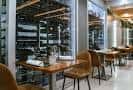 Zona de comedor con mesas de madera y vista a la bodega acristalada del establecimiento