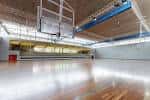 Cancha polideportiva interior con suelo de parqué, canastas y gradas