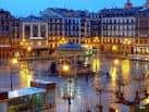 Vista nocturna de la Plaza del Castillo con el quiosco iluminado y edificios históricos al fondo