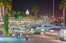 Vista nocturna iluminada del paseo de Muelle Uno con embarcaciones de recreo