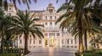 Fachada principal de estilo clásico del Gran Hotel Miramar rodeada de palmeras