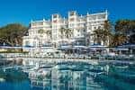 Piscina exterior con el edificio del hotel reflejado en el agua bajo un cielo despejado