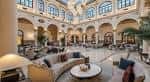 Gran patio interior con arquería clásica, techos altos y mobiliario elegante