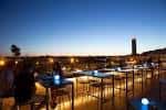 Terraza lounge iluminada al atardecer con vistas a la ciudad de Sevilla