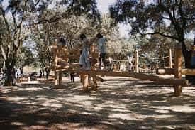Zona de juegos infantiles con estructuras de madera integradas en el entorno natural