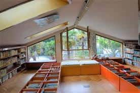 Sala de lectura infantil con estanterías bajas y amplios ventanales con vistas al parque