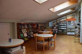 Interior de la biblioteca con mesas circulares y luz natural cenital