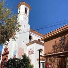 Vista exterior de la torre campanario y la fachada de la Parroquia del Corpus Christi bajo un cielo despejado