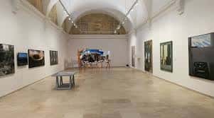 Interior de una sala de exposiciones con techos abovedados y obras de arte