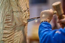 Artesano trabajando una pieza de madera con maza y cincel en el Centro de Artesanía