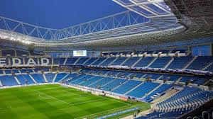 Vista interior del Estadio Reale Arena con las gradas azules y el campo de césped