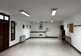 Interior del local social con espacio diáfano y zona de cocina