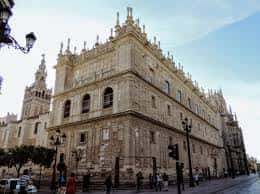 Vista exterior de la fachada de la iglesia con la Giralda de Sevilla al fondo