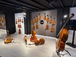 Interior de la galería con exposición de instrumentos de cuerda en paredes y suelo