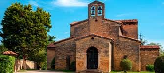 Fachada principal de la iglesia con su característica espadaña y entorno ajardinado