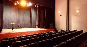 Interior del salón de actos con escenario y filas de butacas