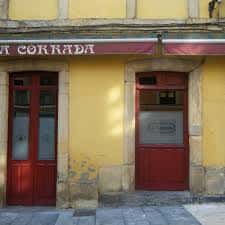 Fachada de estilo tradicional con puertas de madera roja y toldo