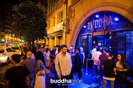 Fachada exterior de la Sala Buddha en Gijón con iluminación nocturna y público en la entrada