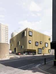 Visualización arquitectónica de la fachada moderna del Brighton Youth Centre con paneles dorados y ventanas cuadradas