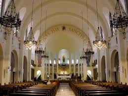 Interior de la iglesia con vista hacia el altar mayor y lámparas colgantes