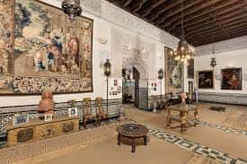 Salón interior señorial con techos de madera, tapices históricos y mobiliario de época