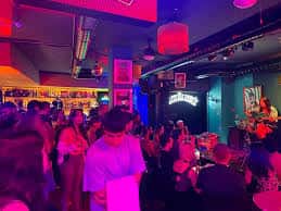 Ambiente de concierto en directo con público y escenario iluminado en el café teatro