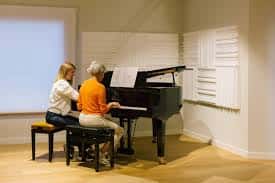 Sesión de enseñanza personalizada con profesora y alumna en un piano de cola