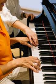 Primer plano de manos tocando las teclas de un piano durante una clase