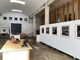 Espacio de exposición con paneles móviles blancos y obras enmarcadas