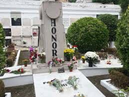 Monumento funerario conmemorativo rodeado de flores y vegetación