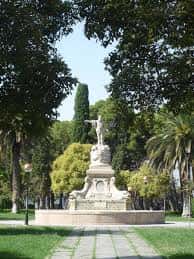 Monumento escultórico rodeado de vegetación y senderos arbolados