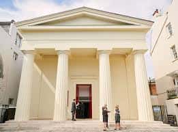 Pórtico de entrada de la iglesia con asistentes en la zona exterior
