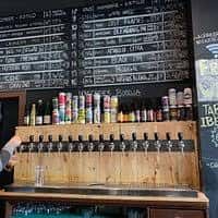 Zona de barra con múltiples grifos de cerveza y pizarra de menú