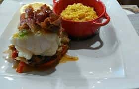 Lomo de bacalao con jamón y guarnición servido en un plato rectangular