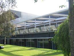 Vista exterior del edificio con fachada de cristal y zonas verdes circundantes